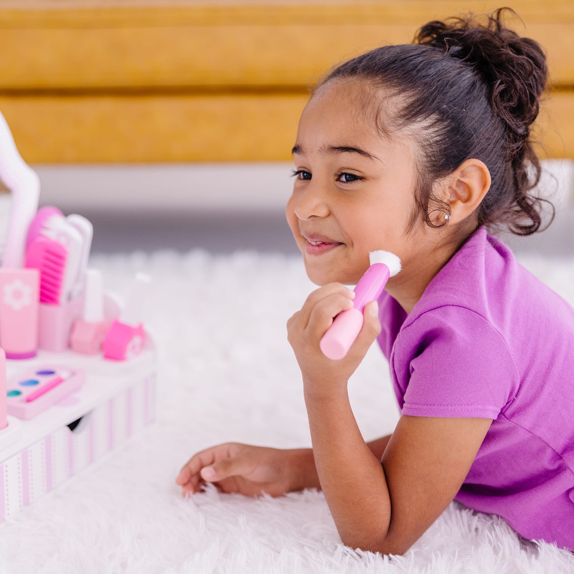 Young girl playing with toy hairbrushes on a fluffy white surface
