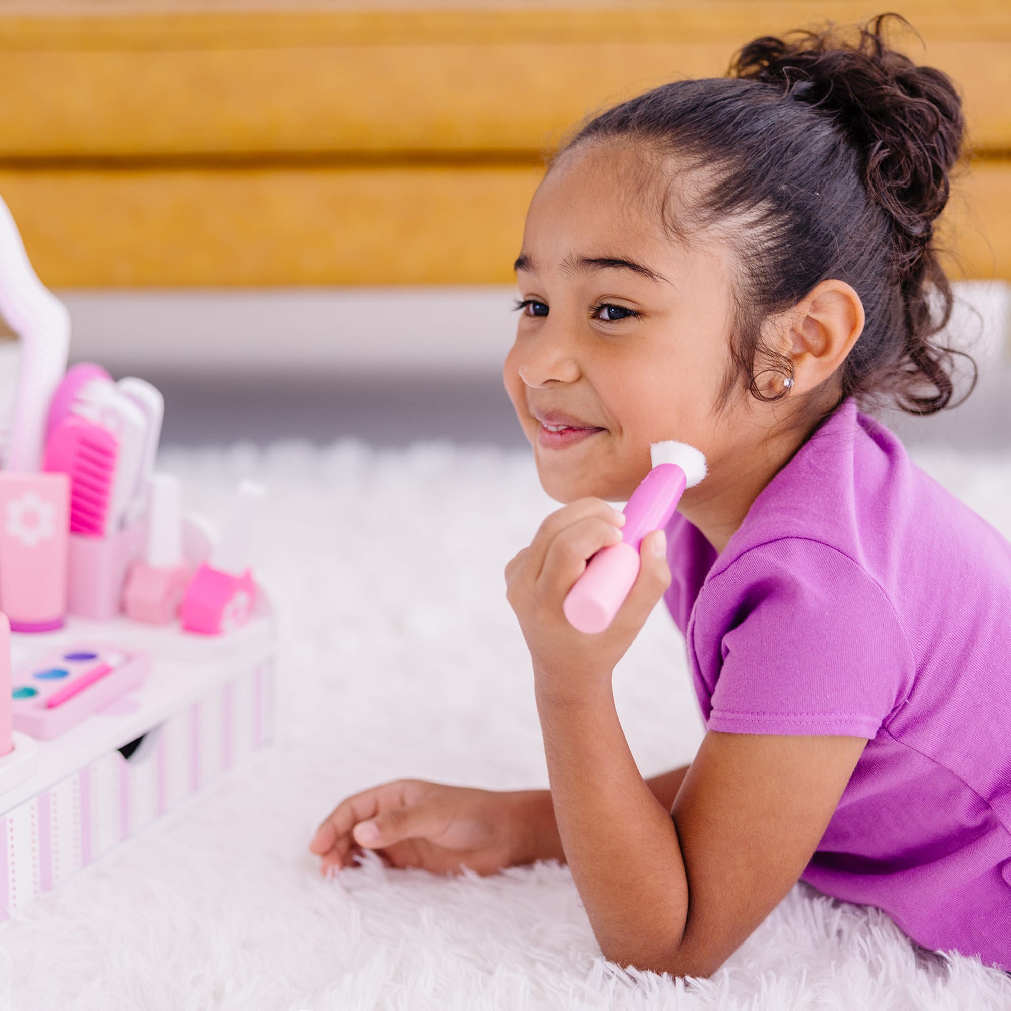 Young girl playing with toy hairbrushes on a fluffy white surface