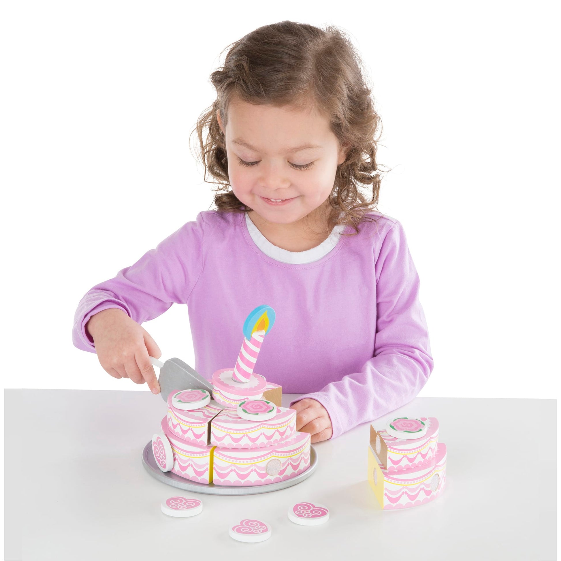 Child playing with a toy cake set on a white background