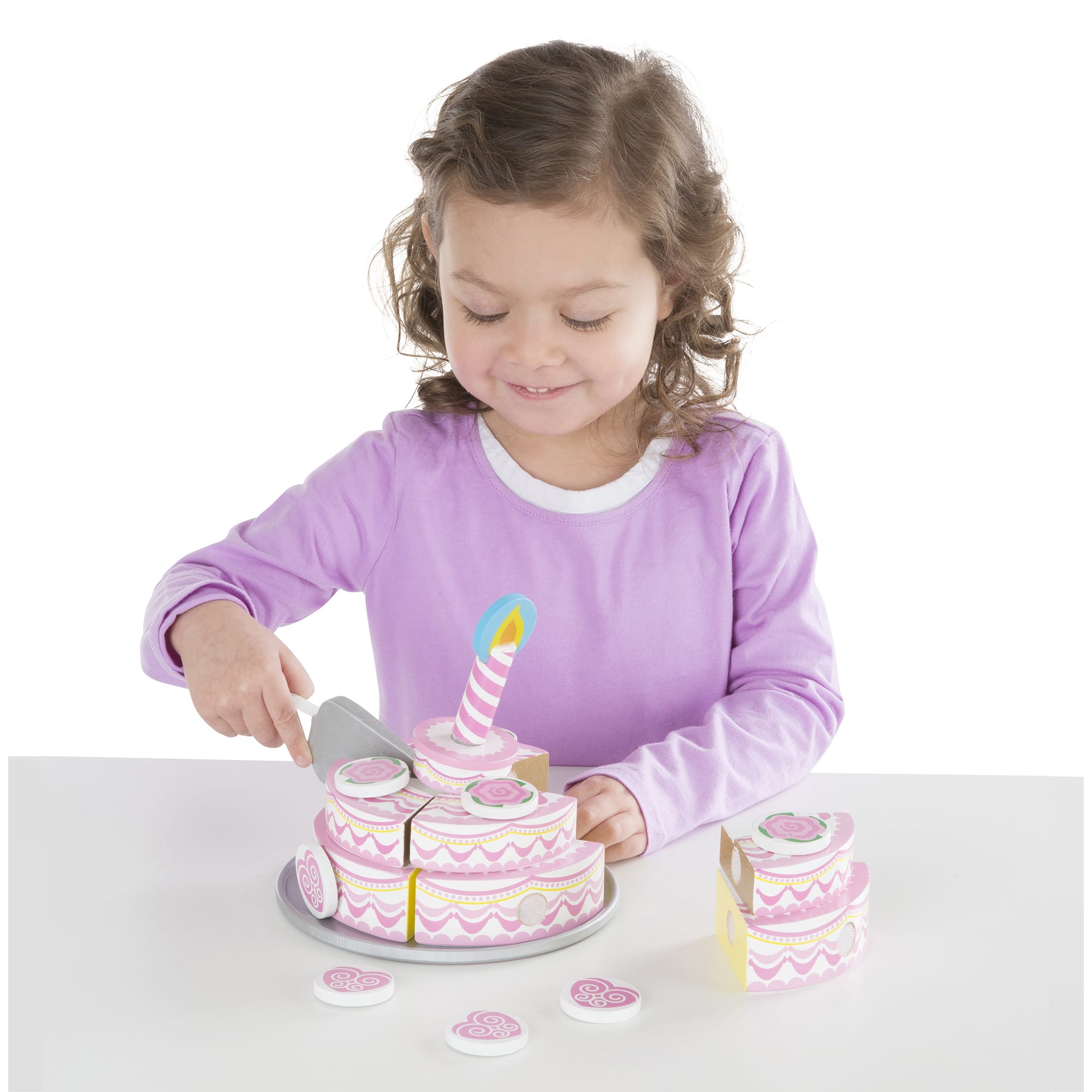 Child playing with a toy cake set on a white background