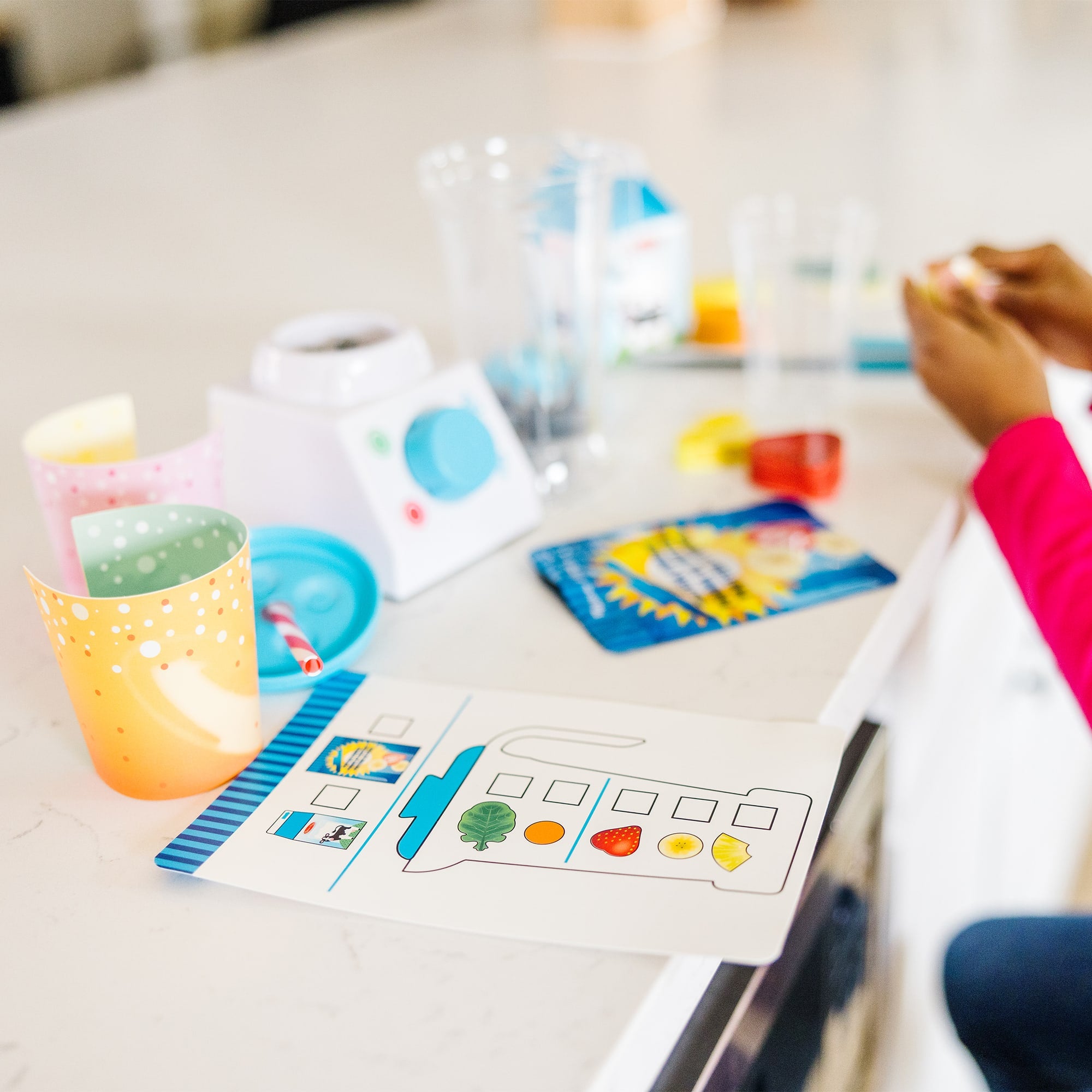 Educational materials on a table with a child's hand reaching out