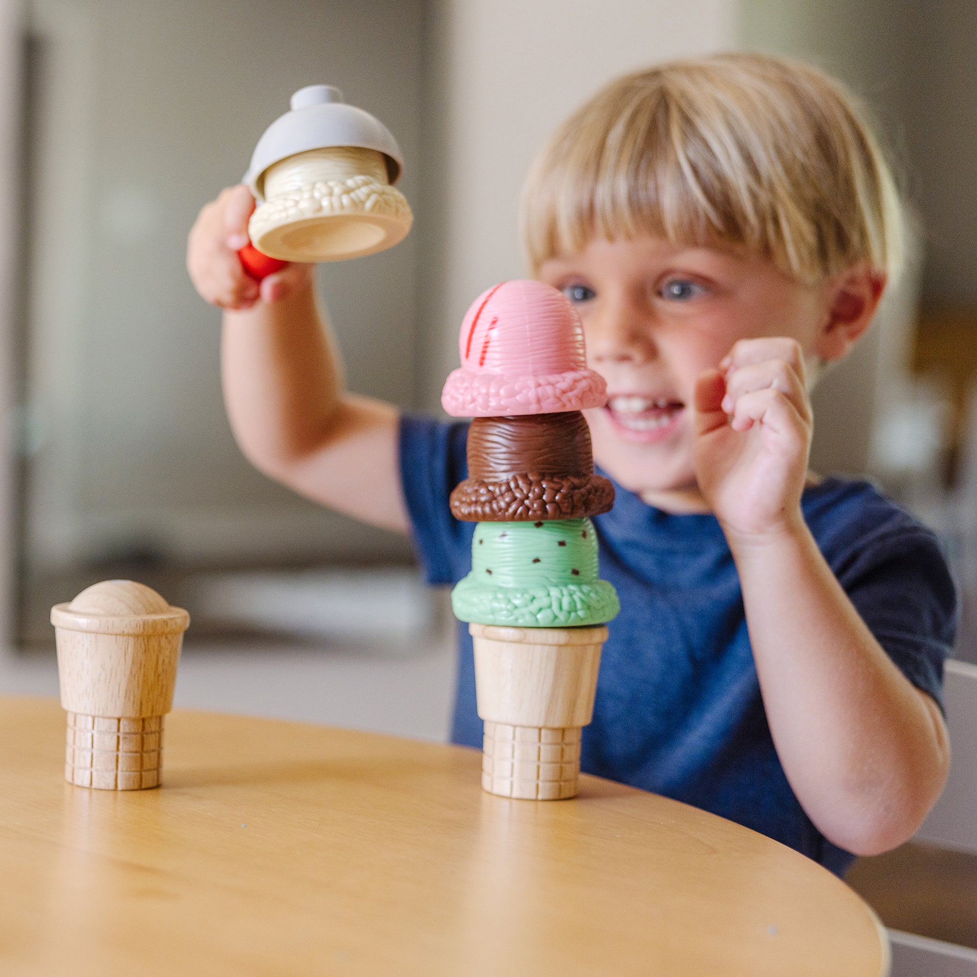 Child playing with toy ice cream cones on a wooden table