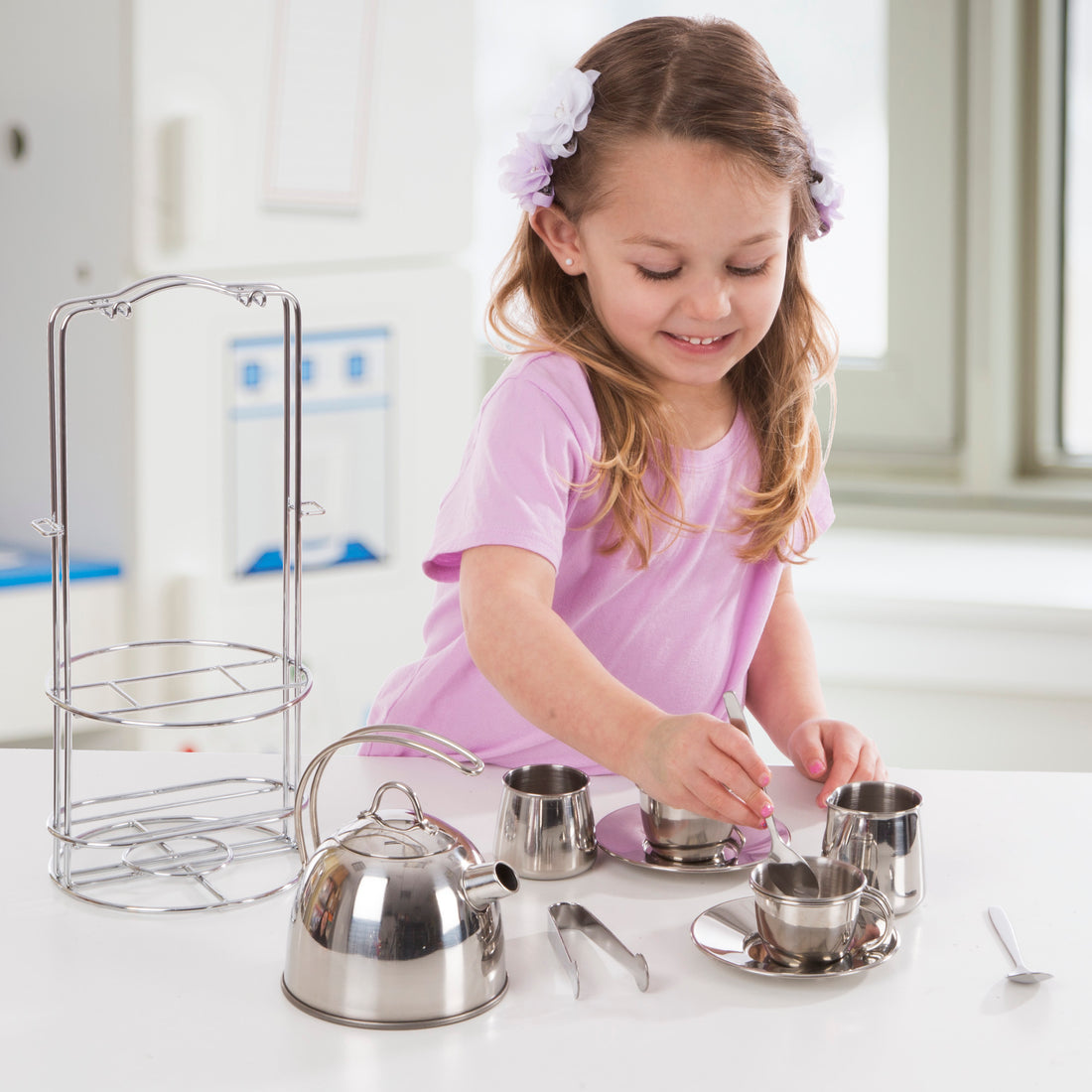 Stainless steel tea set with kettle, cups, saucers, and other utensils on a white background