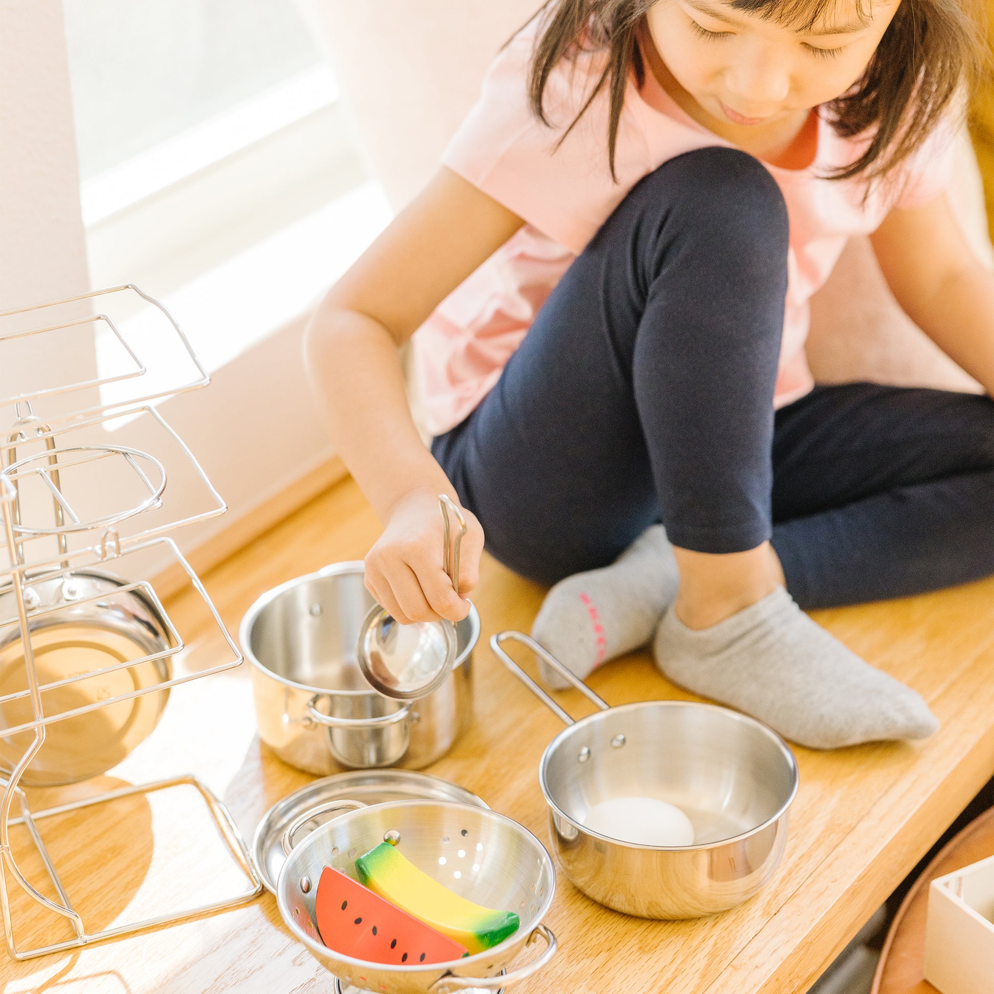 Child playing with metal pots and pans on a wooden floor