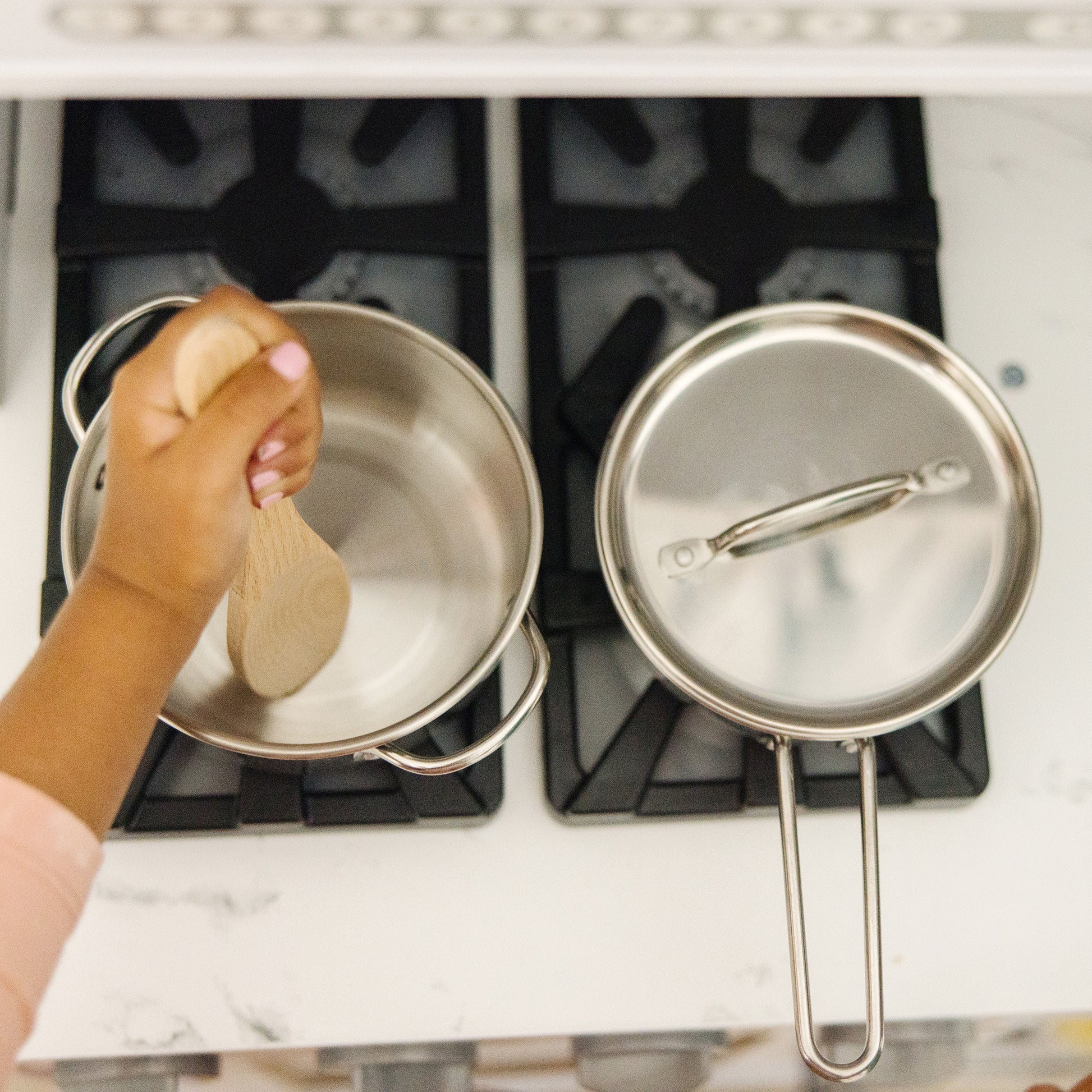 Person stirring a pot on a stove with a wooden spoon