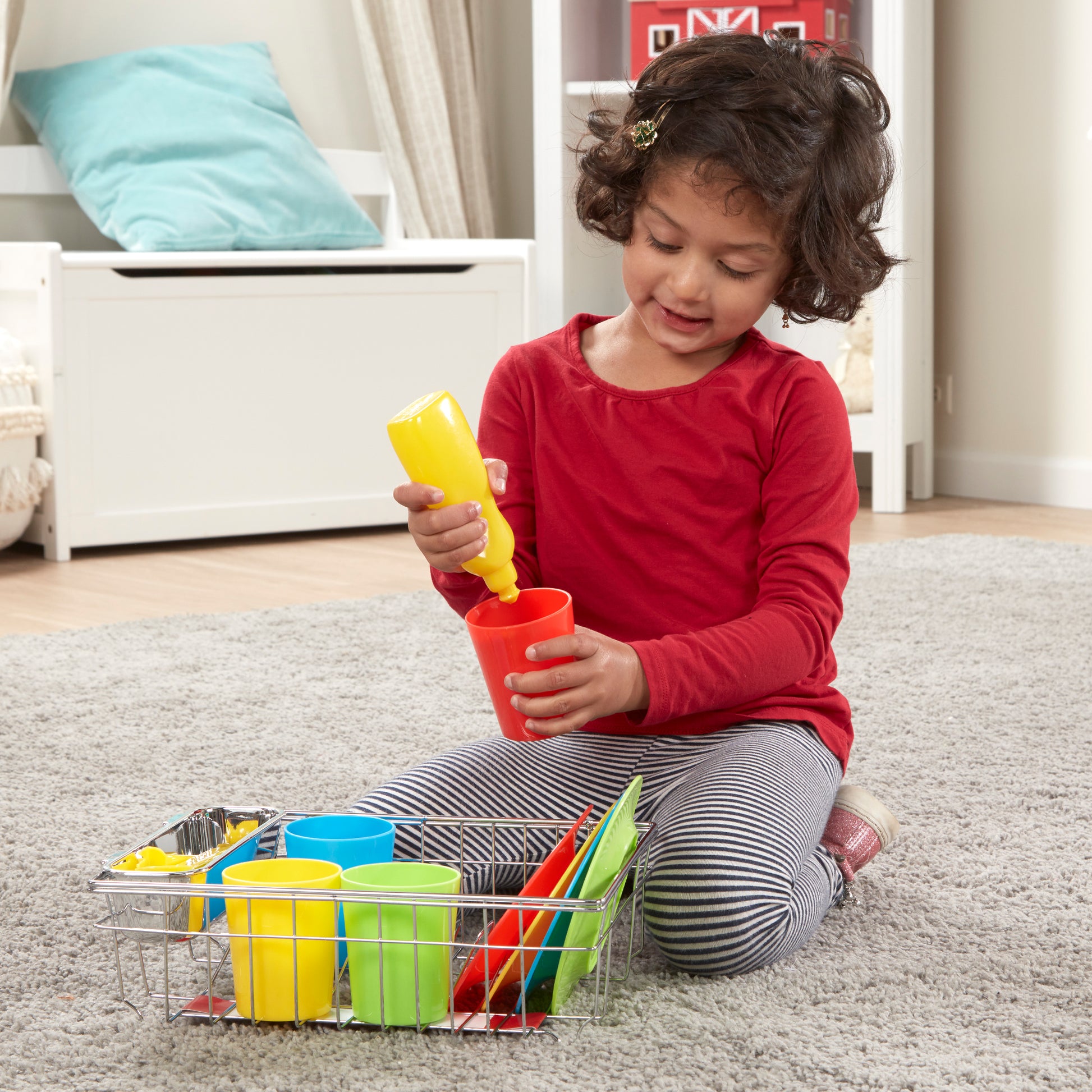 Child playing with colorful toy kitchen set on a carpeted floor.