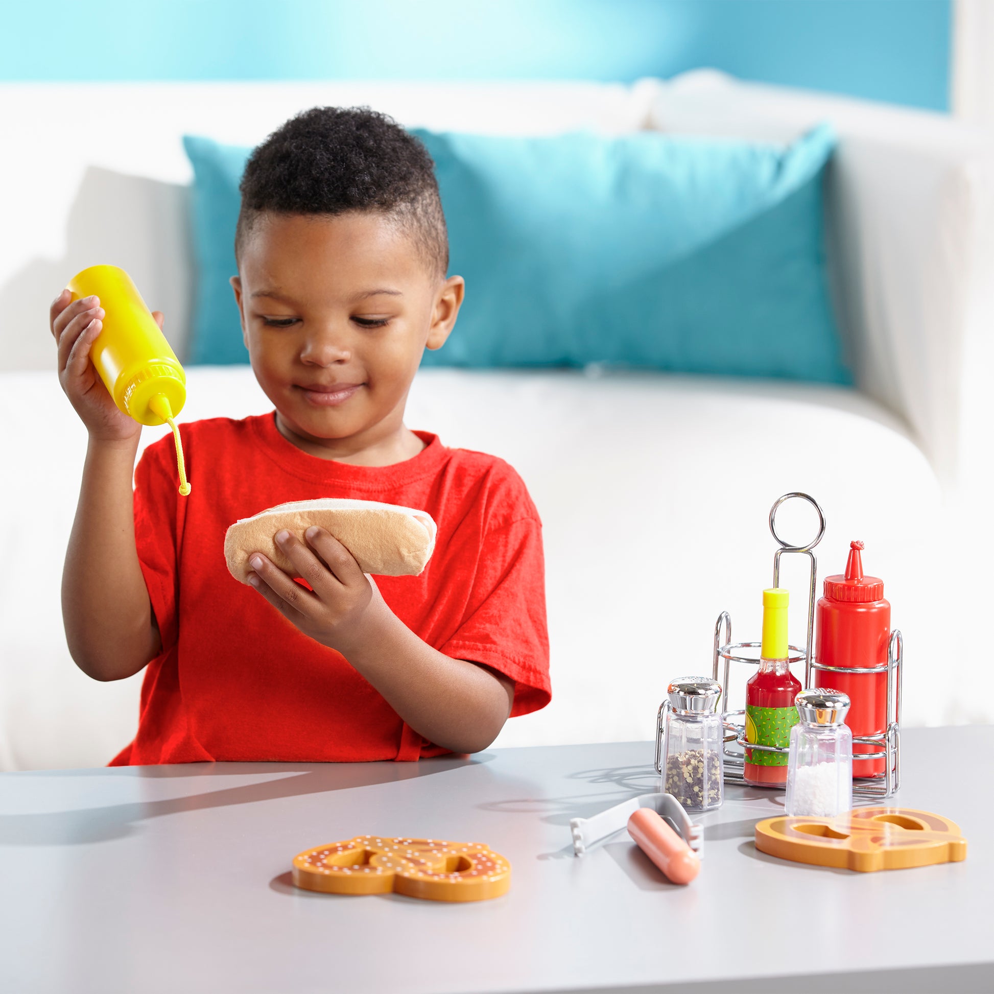 Child playing with toy food and condiments on a table