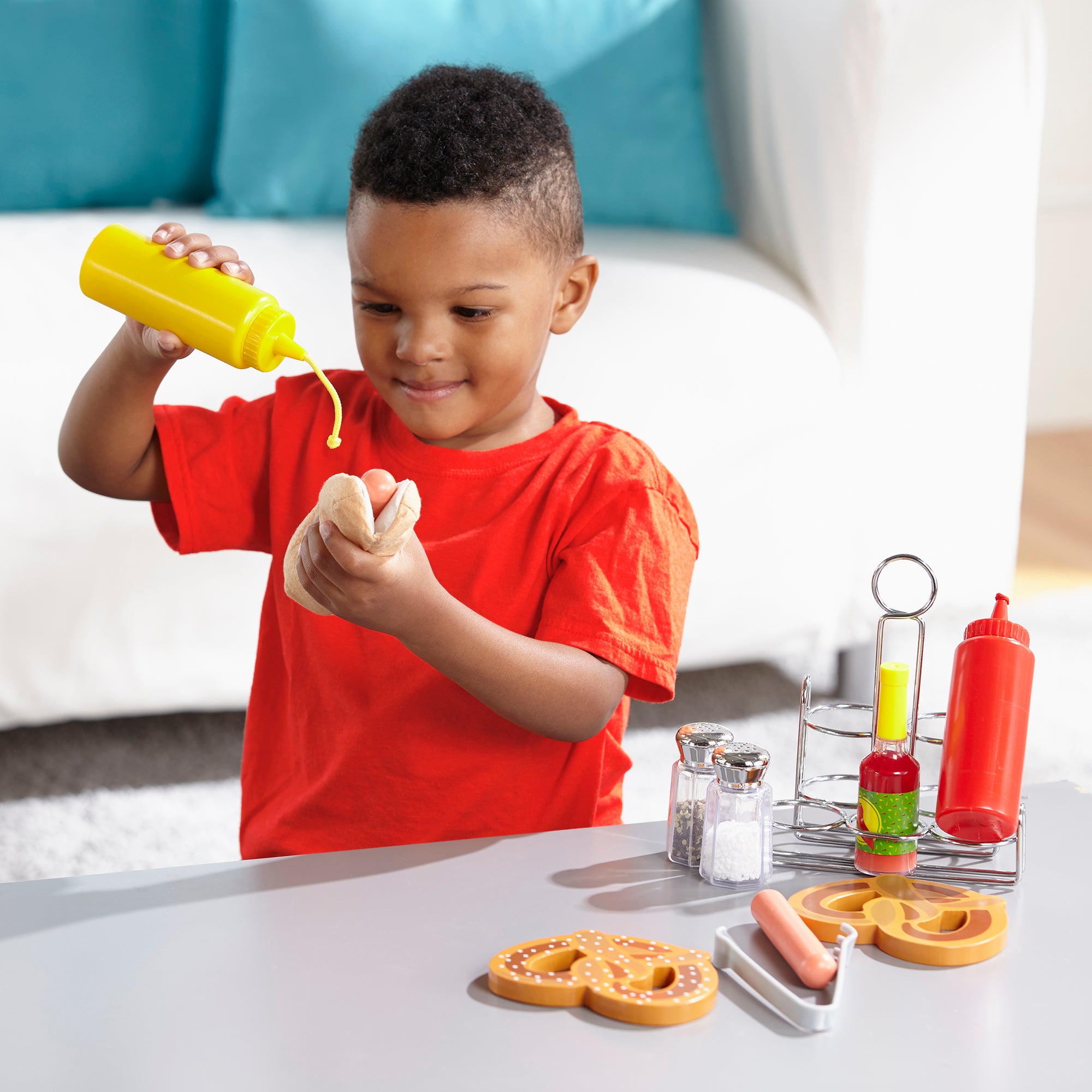 Child playing with toy mustard and ketchup bottles on a table.