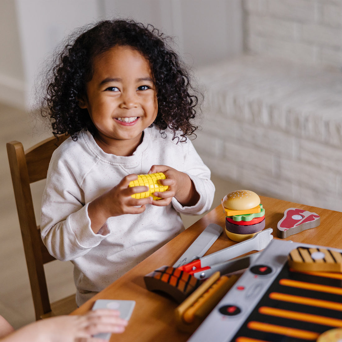 Toy BBQ set with grill, utensils, and food items on a checkered cloth