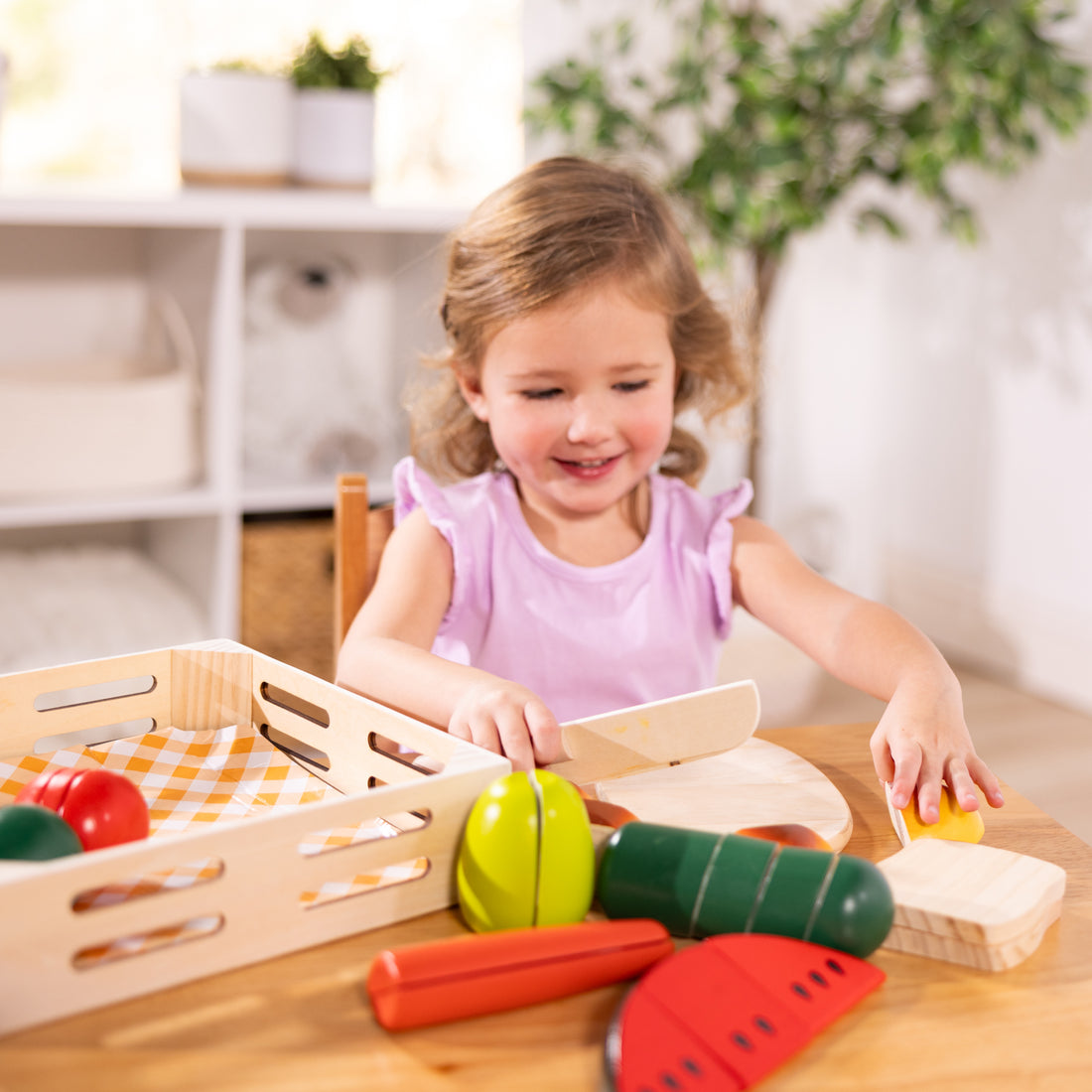 Child playing with wooden toy vegetables and fruits on a table.
