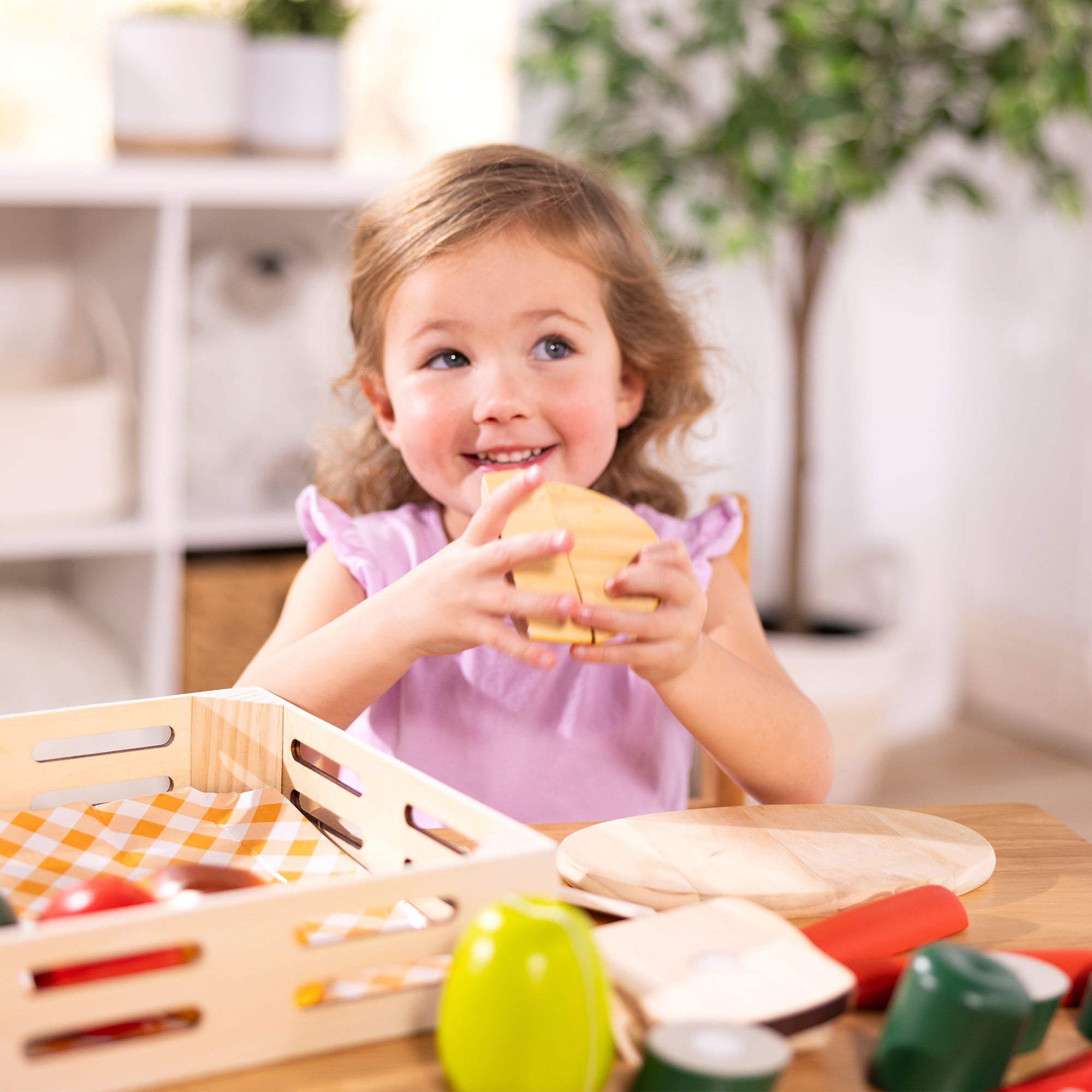 Child playing with toy food items on a table in a home setting