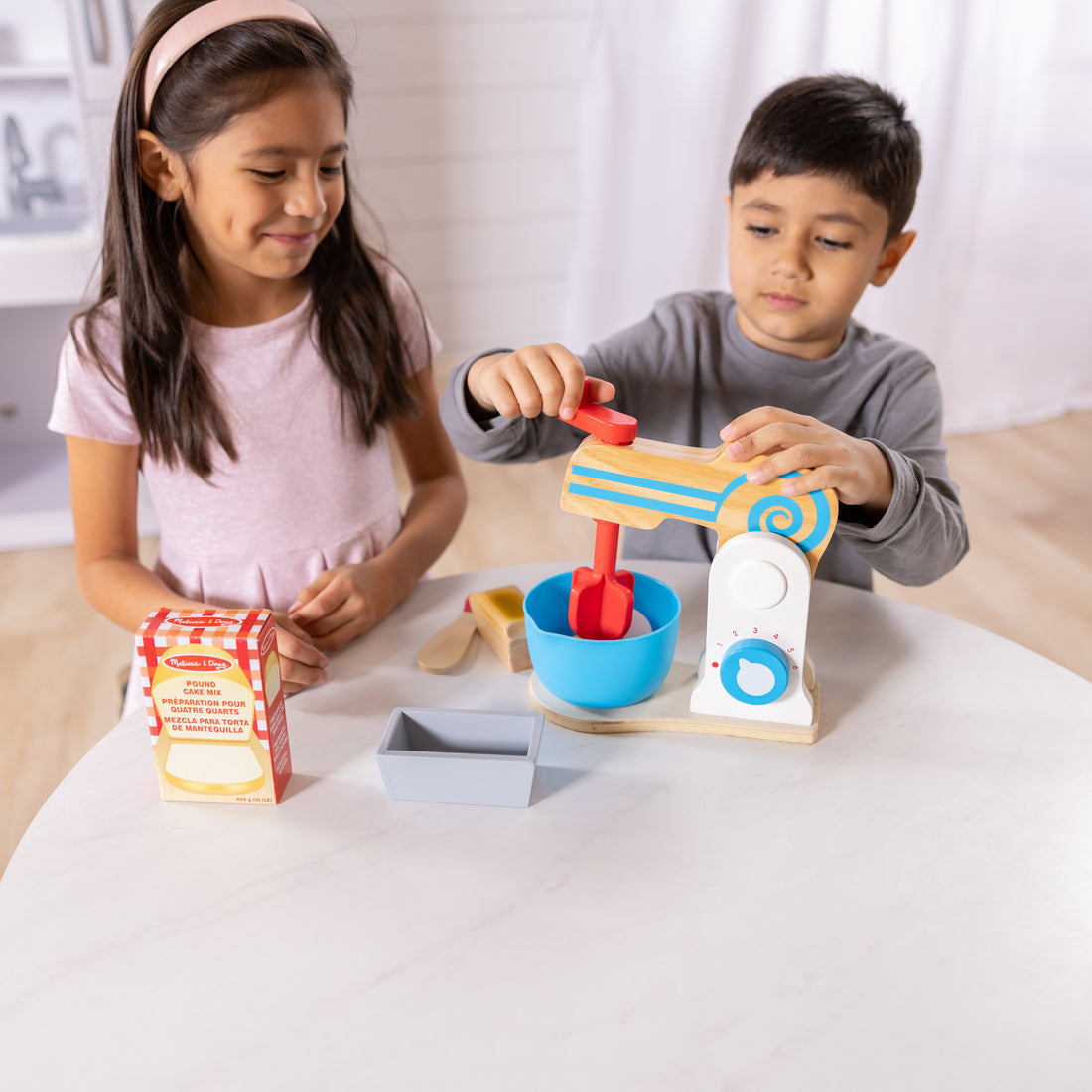 Wooden toy kitchen set with mixer, bowls, and utensils on a white background