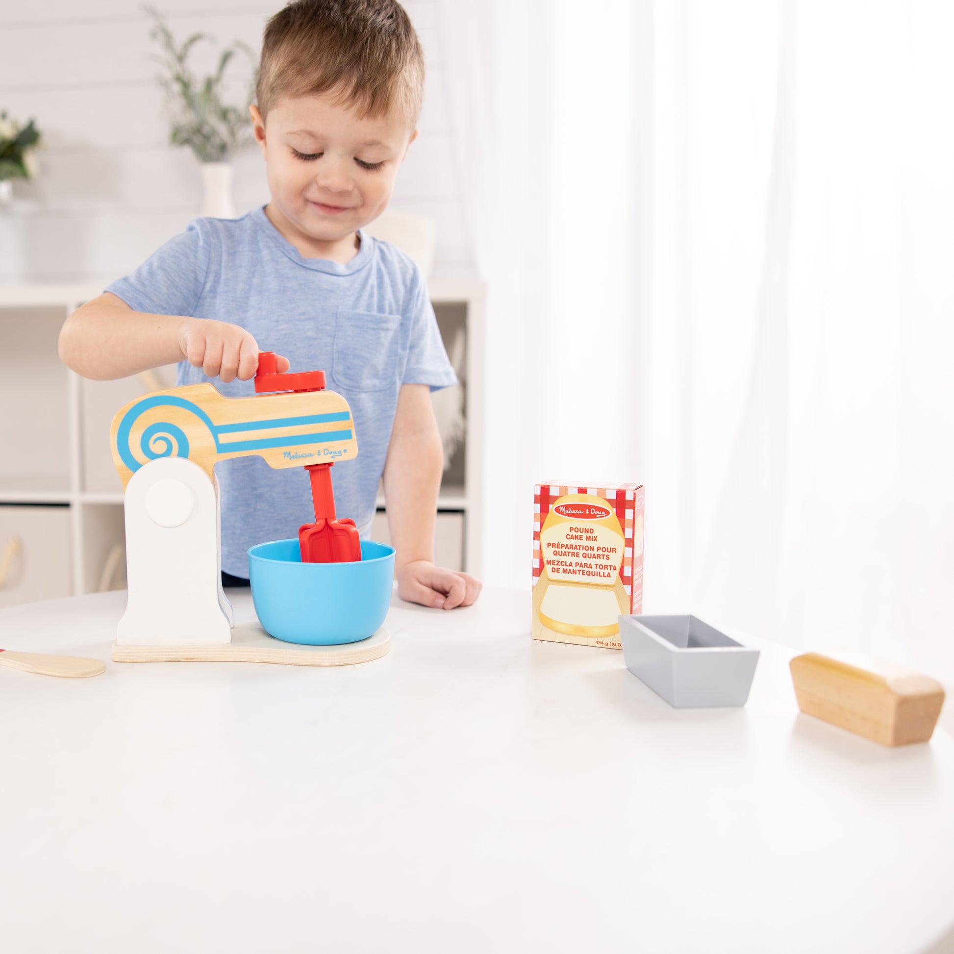 Child playing with a toy kitchen set on a white surface