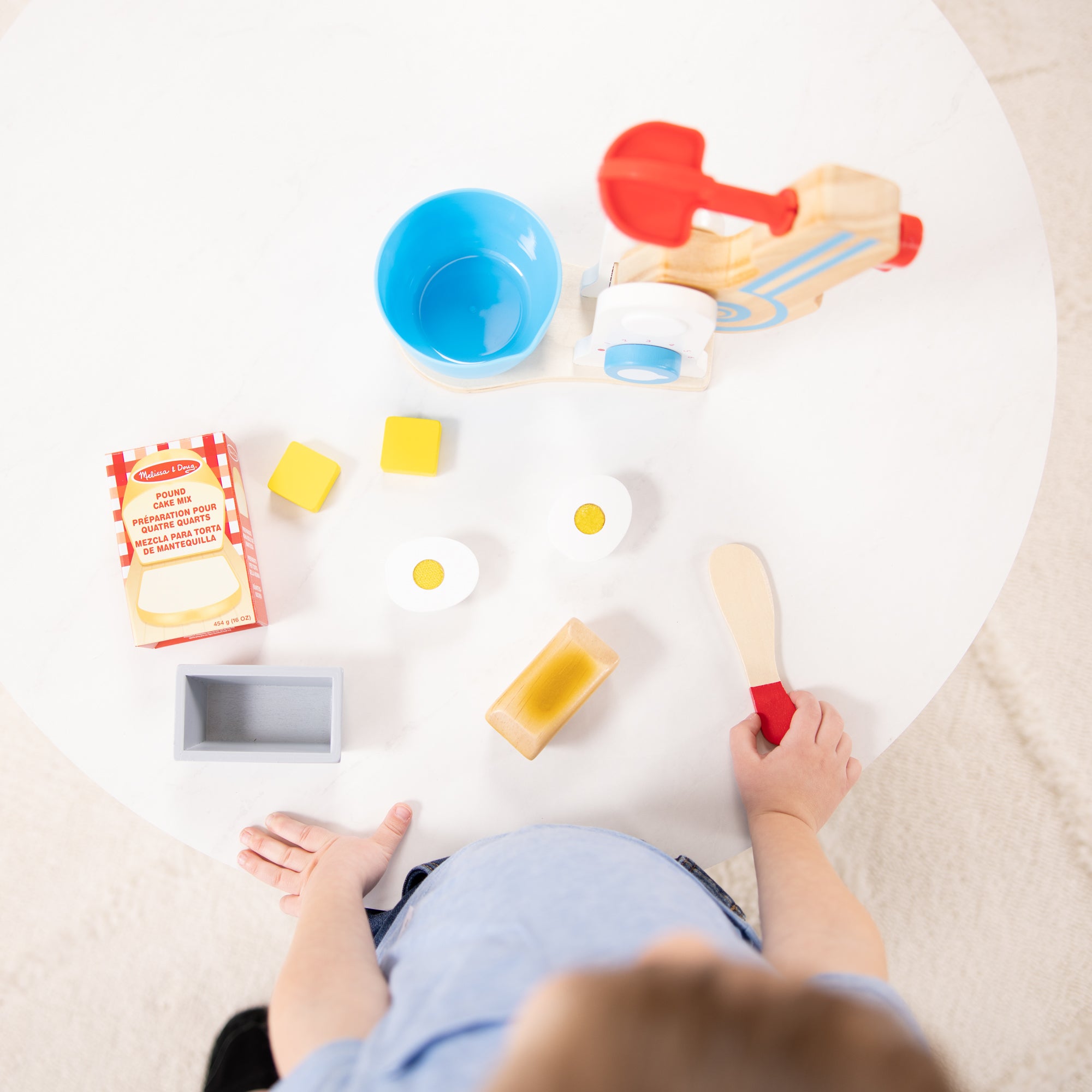 Child playing with colorful kitchen toys on a white surface