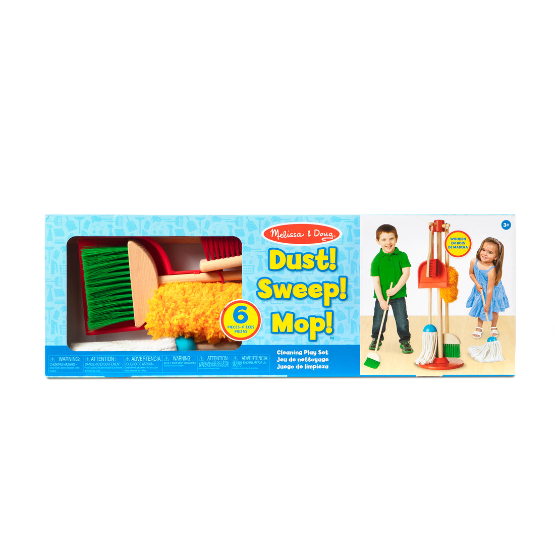 Child in a yellow shirt and brown shorts holding cleaning tools on a bed.