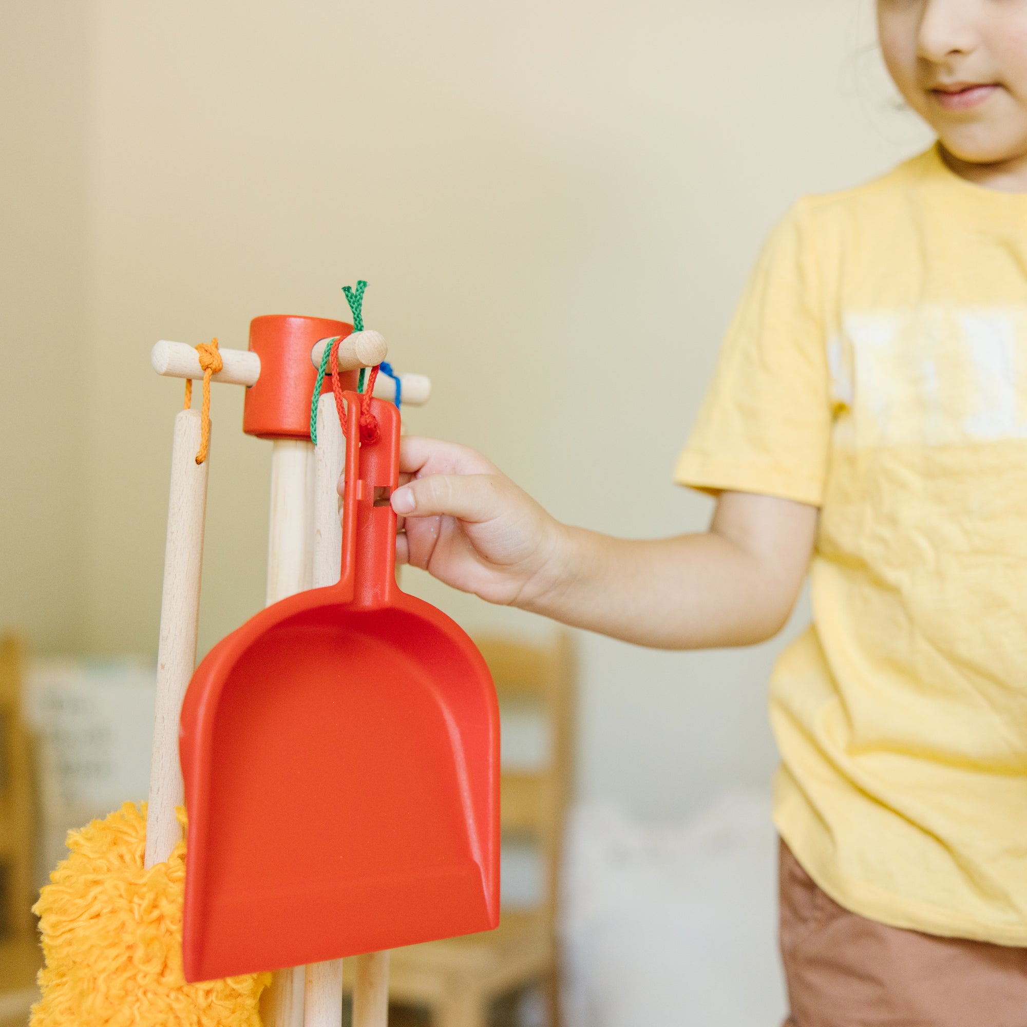 Child holding a red toy shovel with a blurred background