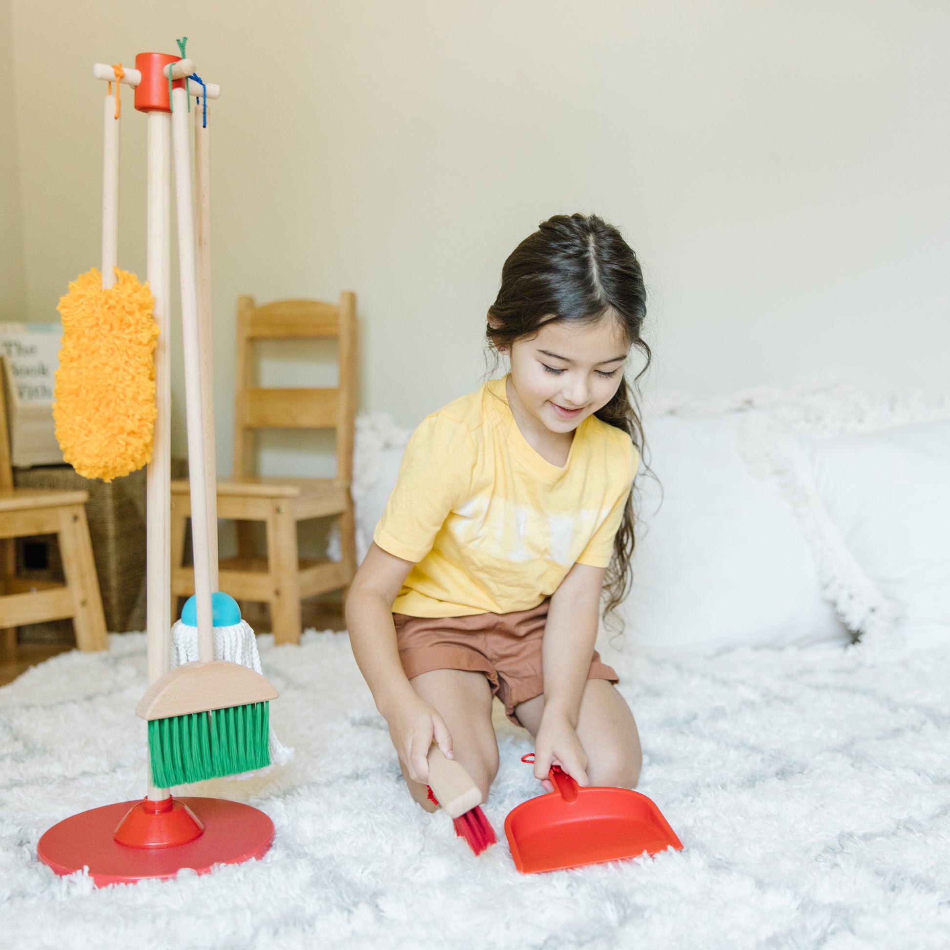 Child playing with toy cleaning set on a carpeted floor