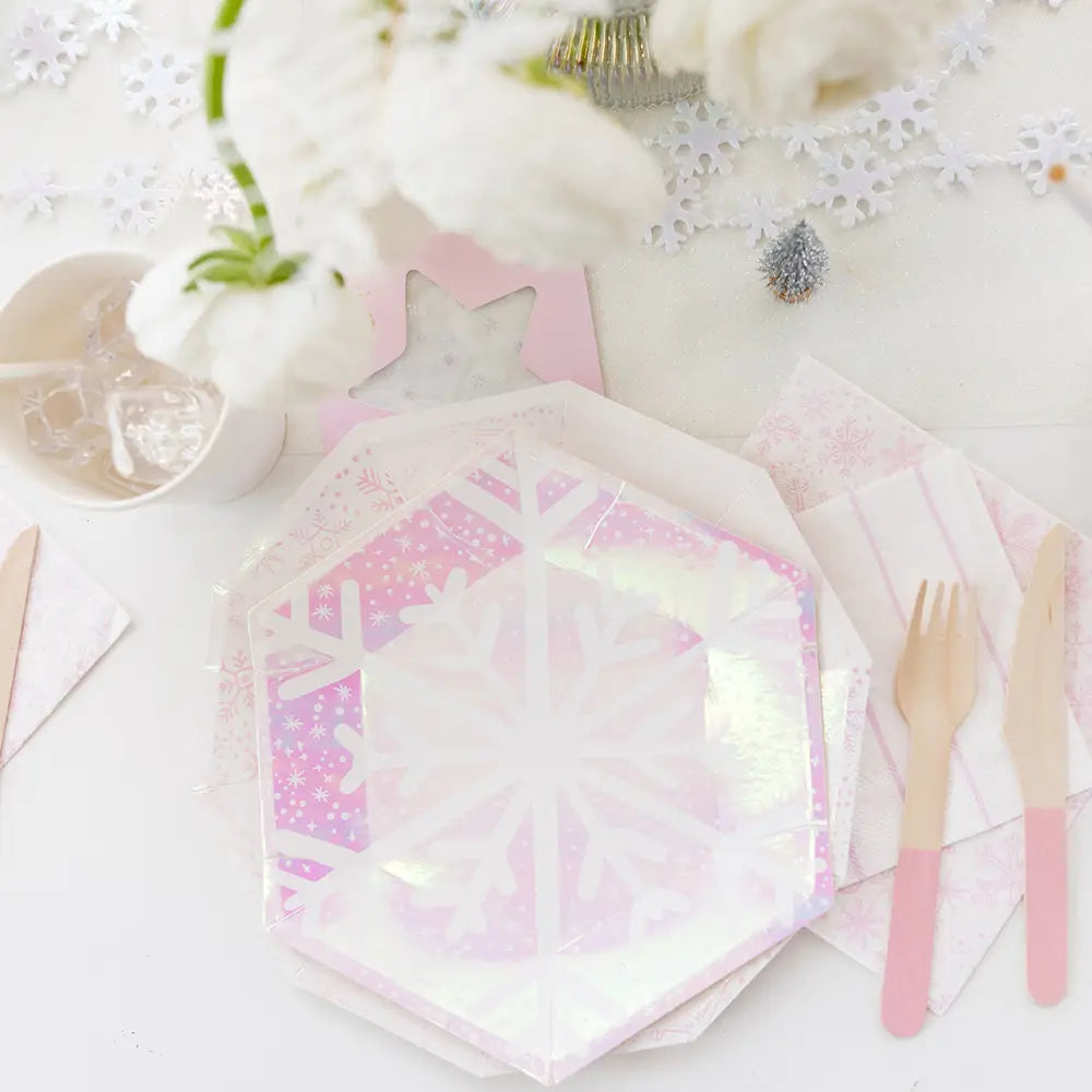 Hexagonal plates with a pink and white pattern on a white surface with cutlery and flowers.