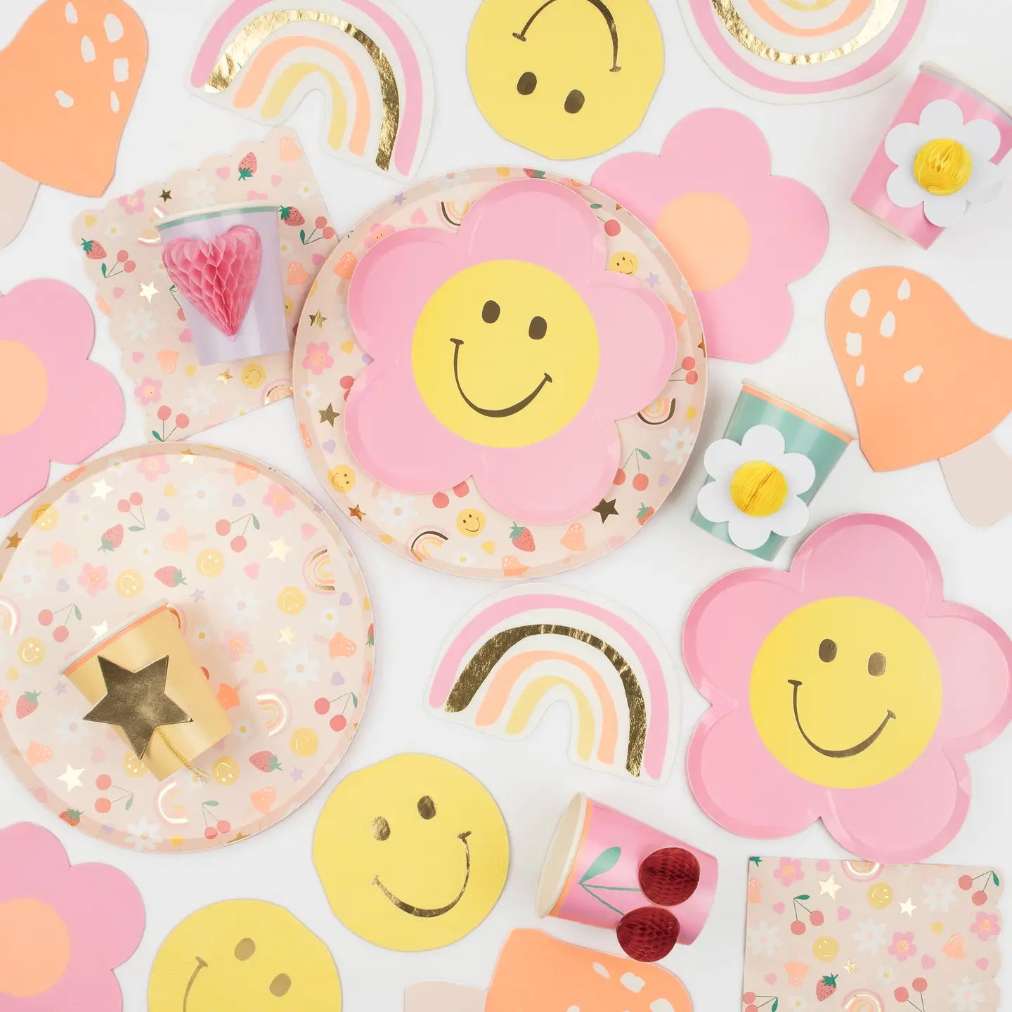Colorful children's party supplies including plates, cups, and napkins with smiley faces and patterns.