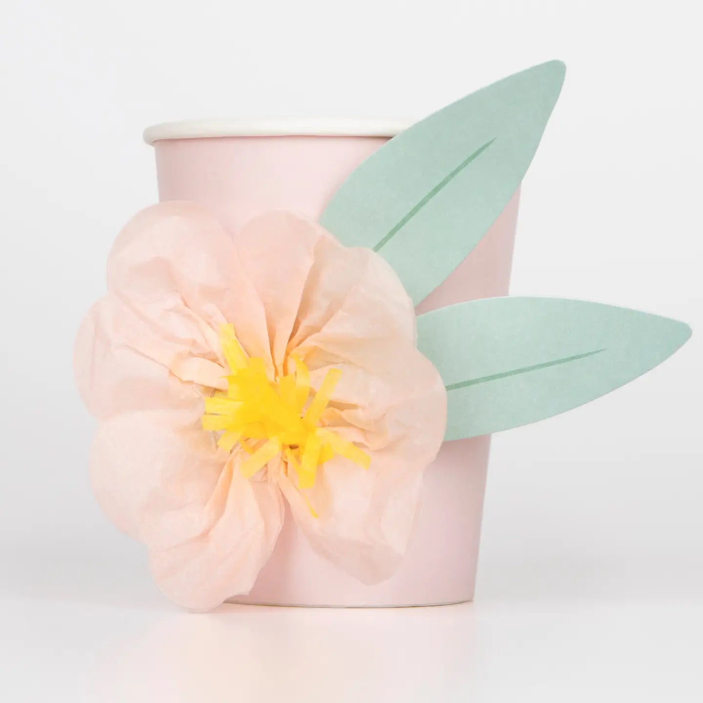 Decorative pink cup with a yellow flower and green leaves on a light gray background