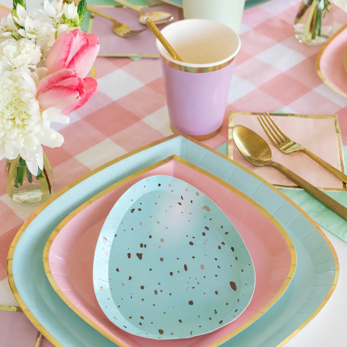 Teal speckled egg-shaped plate on a pink and green platter with floral and cup in the background