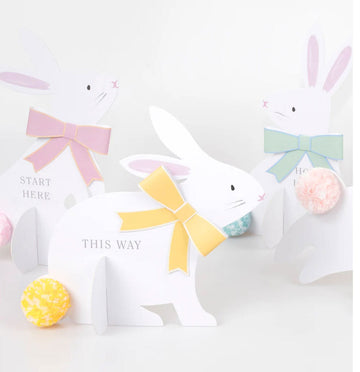 White paper bunny with colorful bow and text on a white background